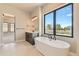 A modern bathroom featuring a soaking tub, large window, and dark vanity with black fixtures at 1210 W 144Th Ct, Westminster, CO 80023