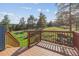 Wooden deck offering scenic views of green field and trees in the background on a sunny day at 5939 S Skyline Dr, Evergreen, CO 80439