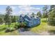 Charming blue two-story home with lush green landscaping and a black asphalt driveway on a sunny day at 5939 S Skyline Dr, Evergreen, CO 80439