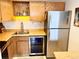 Compact kitchen featuring wooden cabinets, modern appliances, and a stainless steel refrigerator at 8701 Huron St # 3-214, Thornton, CO 80260