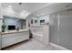 Bright bathroom featuring double sinks, a soaking tub with tile surround, and a glass-enclosed shower at 2321 Ance St, Strasburg, CO 80136