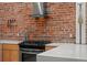 Close up of a kitchen with exposed brick, white countertop and stainless steel gas range at 3354 Vallejo St, Denver, CO 80211