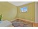 Bright bedroom featuring hardwood floors, a large window, light green walls, and minimalist decor at 6180 W 77Th Pl, Arvada, CO 80003