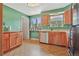 Cozy kitchen with wooden cabinets, laminate countertops, green walls, and views from the window at 6180 W 77Th Pl, Arvada, CO 80003