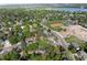 A sunny aerial view reveals a neighborhood near a school, baseball field, and a serene lake at 7695 S Harlan St, Littleton, CO 80128