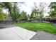 Open backyard featuring a concrete patio, lush lawn, gravel area, and a wooden fence for privacy at 7695 S Harlan St, Littleton, CO 80128