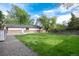 Spacious backyard with well-maintained lawn, gravel area, and access to the rear of the house at 7695 S Harlan St, Littleton, CO 80128