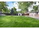 Expansive backyard featuring lush lawn, mature trees, wooden fence, and a storage shed for outdoor equipment at 7695 S Harlan St, Littleton, CO 80128