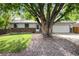 Charming ranch-style home with brick accents and a lush front yard shaded by a mature tree at 7695 S Harlan St, Littleton, CO 80128