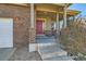 Covered front porch with brick pillars and a red front door on a brick home exterior at 1960 E 166Th Dr, Thornton, CO 80602