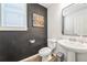 Stylish half-bathroom boasts dark accent wall, modern vanity, and trendy guitar artwork at 19197 E 64Th Ave, Denver, CO 80249