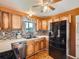 Traditional kitchen with wood cabinets, mosaic backsplash, black appliances, and a ceiling fan at 15769 E Greenwood Dr, Aurora, CO 80013