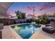 Backyard pool with stone waterfall feature, mature landscaping, and poolside lounge chairs at dusk at 1609 S Clayton St, Denver, CO 80210