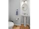 Cozy half-bathroom featuring pedestal sink, decorative mirror, and hardwood floors at 997 Dogwood Dr, Golden, CO 80401