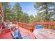 Red wooden deck offering ample space for outdoor dining and relaxation amid a beautiful forest setting at 997 Dogwood Dr, Golden, CO 80401