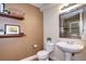Cozy bathroom with pedestal sink, wood shelves, and framed mirror at 7329 Arco Iris Ln, Castle Pines, CO 80108