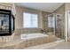 Elegant bathroom featuring a corner soaking tub, stone tile detail, and glass enclosed shower, exuding comfort and relaxation at 7329 Arco Iris Ln, Castle Pines, CO 80108