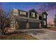 Two-story house with gray siding, stone accents, and a two-car garage at dusk at 11729 Elmer Linn Dr, Longmont, CO 80504
