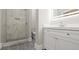 Modern bathroom featuring a tiled shower with a gray mosaic floor and a white vanity with storage at 8250 W 63Rd Ave, Arvada, CO 80004