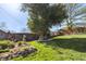 Large backyard featuring a mature shade tree, deck with dining, lush lawn, rock retaining wall, and garden areas at 760 Deframe St, Golden, CO 80401