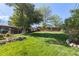 Extensive green backyard with mature trees, rock retaining wall, gardens, lush green lawn, and private fencing at 760 Deframe St, Golden, CO 80401