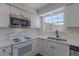 Bright kitchen features white cabinets, stainless steel microwave, and a double basin sink under a window at 8780 E Yale Ave, Denver, CO 80231