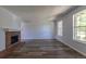 Spacious living room featuring wood flooring, a traditional brick fireplace, and natural light from two windows at 8780 E Yale Ave, Denver, CO 80231