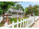 Exterior shot showing a gray single-story home, white picket fence, and a well feature in the yard at 725 Knox Ct, Denver, CO 80204
