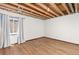 Basement with wood-look floor, white walls, and a partially finished ceiling with an uncovered duct at 5602 County Road 15, Fort Lupton, CO 80621