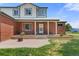 Close up of a charming home's front entrance with a red brick facade and landscaped yard at 5602 County Road 15, Fort Lupton, CO 80621