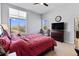 Main bedroom with ceiling fan, large windows, comfortable furniture, and wood dresser at 5110 E 64Th Ave, Commerce City, CO 80022