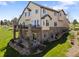 A beige two-story home featuring a stone foundation, outdoor balcony, manicured yard, and professional landscaping at 16223 River Haven Way, Morrison, CO 80465
