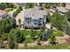 An aerial view displays a beautiful home with an expansive deck, a lush yard, and mature trees at 5665 Vistancia Ct, Parker, CO 80134