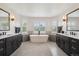 Elegant bathroom with double vanities, a freestanding tub, and large windows providing natural light and outdoor views at 5665 Vistancia Ct, Parker, CO 80134