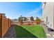 Fenced backyard featuring synthetic grass, rock beds, and a well-maintained lawn at 10512 Truckee St, Commerce City, CO 80022