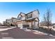 Inviting two-story home with tan siding, a brick driveway, and a covered porch, blending charm and curb appeal at 10512 Truckee St, Commerce City, CO 80022