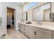 Bathroom featuring dual vanities, a clerestory window, and an entrance to the large walk-in closet at 7169 Canyon Sky Trl, Castle Pines, CO 80108