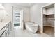 Bright bathroom showcasing soaking tub, walk-in closet and white tiled floors at 2548 Wesley Ln, Lafayette, CO 80026