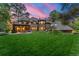 Expansive backyard featuring a large brick home, outdoor patio, and manicured lawn at dusk at 4600 E 3Rd Ave, Denver, CO 80220
