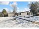 Ranch style home with white brick exterior, attached garage, and snowy front yard at 770 S Arbutus St, Lakewood, CO 80228