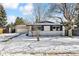 Charming ranch home with white brick exterior, attached garage, and snowy front yard at 770 S Arbutus St, Lakewood, CO 80228