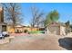 Spacious backyard with a brick patio, detached garage with basketball hoop, seating, and mature trees at 6411 E 64Th Ave, Commerce City, CO 80022