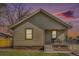 Charming single story home featuring vinyl siding, a cozy front porch and a well-kept front lawn at sunset at 6411 E 64Th Ave, Commerce City, CO 80022
