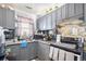 Efficient kitchen layout with tiled backsplash, gray cabinets, granite counters, and modern appliances at 6411 E 64Th Ave, Commerce City, CO 80022