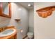 Charming bathroom with custom wood accents, a sink, a toilet, and decorative shelving at 10991 E Vassar Dr, Aurora, CO 80014