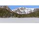 Picturesque frozen lake view surrounded by mountains and lush green forest with rustic cabins at 563 Brook Dr, Idaho Springs, CO 80452