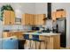 Bright kitchen featuring wooden cabinets, granite counters, black appliances and a breakfast bar with modern stools at 1438 Little Raven St # 407, Denver, CO 80202