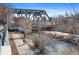 A riverside view shows the rusted iron bridge, river path, and a Personal and dog on a walk at 1438 Little Raven St # 407, Denver, CO 80202