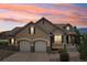 Stunning home exterior with a two-car garage, stone accents, and beautiful sunset sky at 15947 Bridle Ridge Dr, Monument, CO 80132