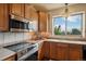 Close up of stainless appliances, wood cabinets and tile backsplash in this modern kitchen at 15947 Bridle Ridge Dr, Monument, CO 80132